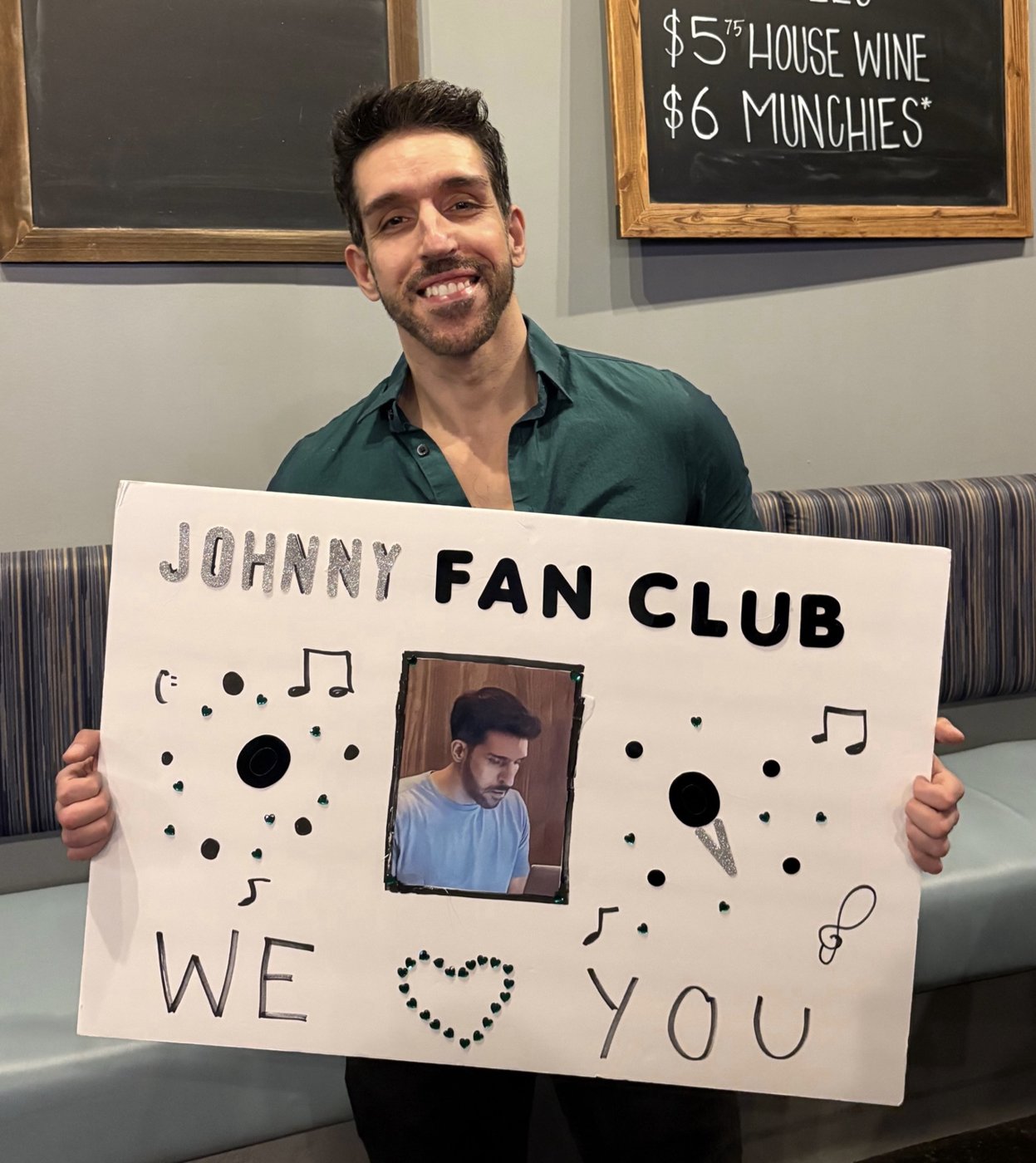 Johnny smiling and holding a handmade Johnny Fan Club sign