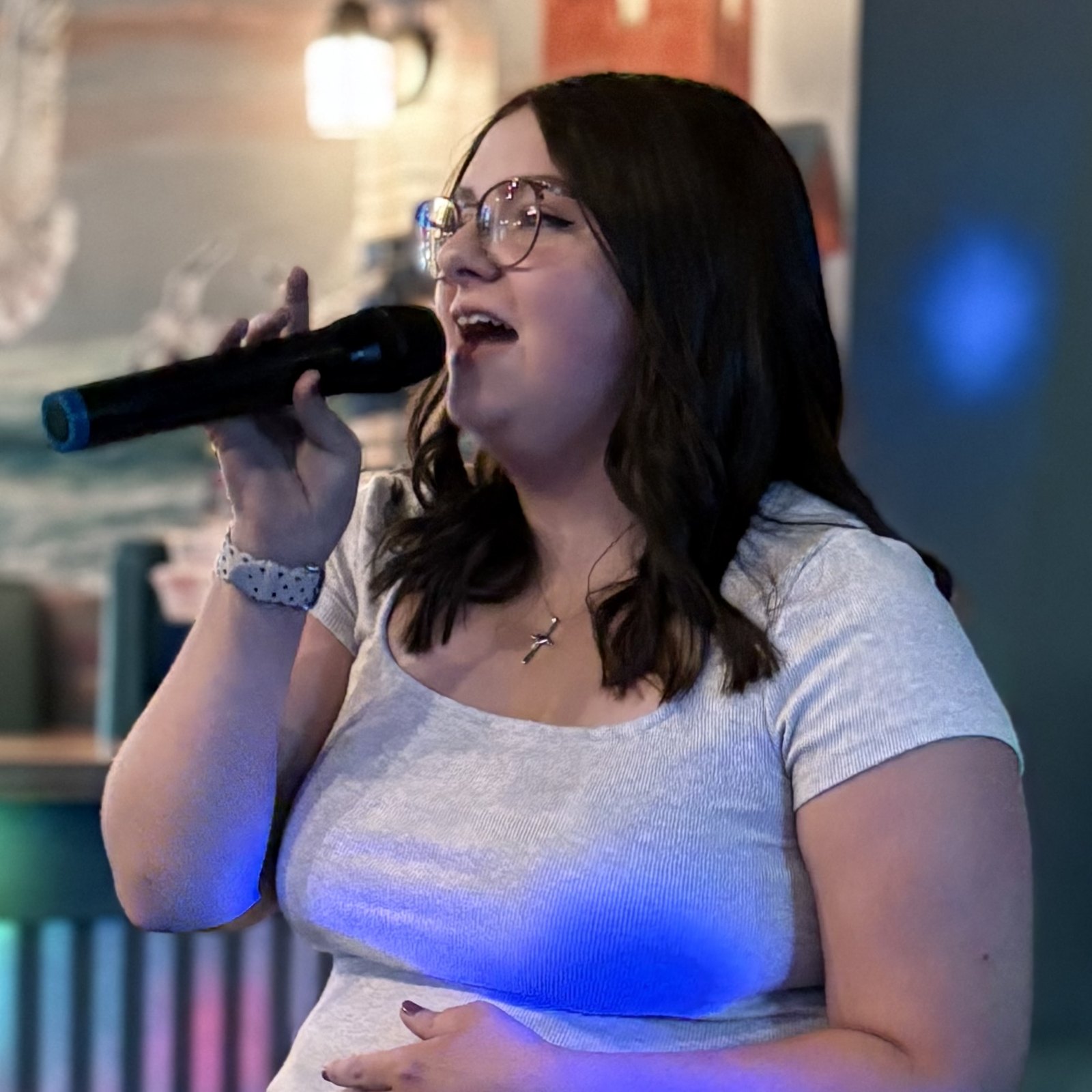 Woman singing into a microphone at karaoke under blue lights